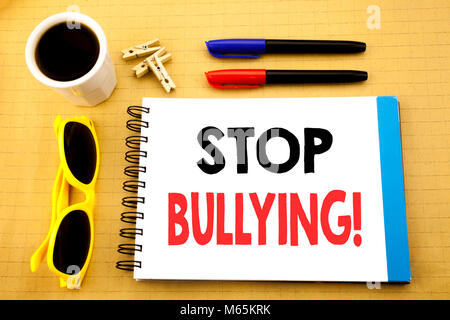 La scrittura di un testo che mostra arrestare il bullismo. Il concetto di business per la prevenzione problema Bully scritto su una nota adesiva con copia spazio su legno Sfondo legno wit Foto Stock