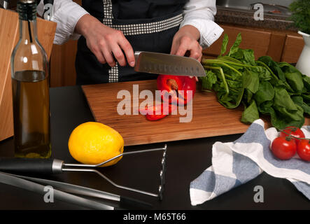 La donna la cottura in cucina rendendo il cibo sano. Cuocere il taglio di vegetali Foto Stock