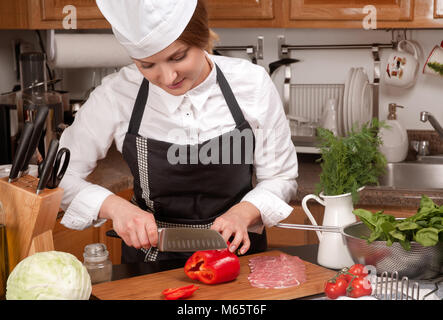 La donna la cottura in cucina rendendo il cibo sano. Cuocere il taglio di vegetali Foto Stock