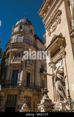 Close-up di edifici con statue, dettagli decorativi sulle pareti e cielo blu a Nimes. Situato nella regione di Occitanie nel sud della Francia. Foto Stock