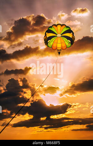 Il parasailing drammatico nel tardo pomeriggio di sole sulla spiaggia bianca a Puerto Galera su Oriental Mindoro Island, Filippine. Foto Stock