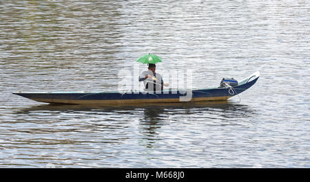 Pescatore sul fiume Sarawak Kuching, prendendo una pausa pranzo con green parasol hat Foto Stock