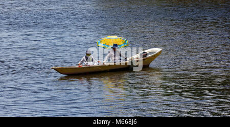 Due uomini la pesca usando un ombrellone per ombra Foto Stock