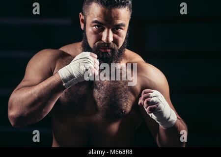 L'uomo boxe allenamento sul ring. Maschio caucasico boxer di guanti neri Foto Stock