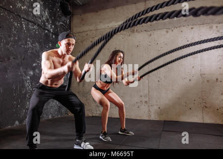 Donna e uomo giovane la formazione insieme facendo combattendo la corda allenamento Foto Stock