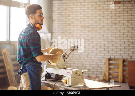 Attraente uomo iniziare facendo lavori in legno in falegnameria Foto Stock