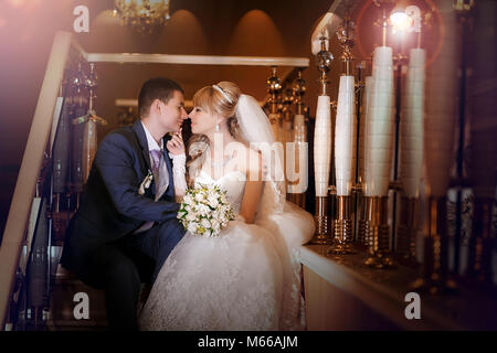 Felice lo sposo e la sposa a sedersi su steirs nella hall dell'hotel Foto Stock