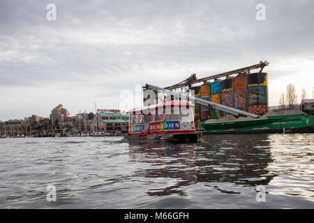 Il centro di Vancouver, British Columbia, Canada - 28 Gennaio 2017 - un piccolo taxi traghetto è di equitazione in False Creek durante una vibrante tramonto in inverno. Foto Stock