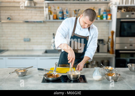 Focalizzato lo chef prepara una polenta in cucina del ristorante del processo di cottura Foto Stock