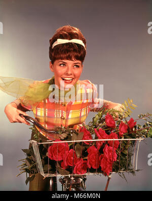 Anni sessanta sorridente ragazza TEEN CON TAQUINÉ BRUNETTE pettinature pettinatura equitazione Bicicletta con rose rosse BOUQUET IN BASKET - kf4337 HAR001 HARS LIETA GIOIA LIFESTYLE FEMMINE STUDIO SHOT BIKE ROSE SALUBRITÀ UNA SOLA PERSONA spazio copia di metà lunghezza LADIES ragazza adolescente fiducia archetto NOSTALGIA DI TRASPORTO 16-17 anni BRUNETTE felicità benessere stili di svago di acconciatura sorrisi di ricreazione gioiosa adolescente Moda Pettinatura novellame taquiné giovane donna adulta BANGS grandi capelli biker pettinature etnia caucasica capelli BOW in vecchio stile persone Foto Stock