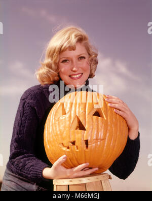 Anni sessanta sorridente DONNA BIONDA AZIENDA Jack-O-Lantern zucca intagliata guardando telecamera - KH2181 HAR001 HARS STATI UNITI SQUASH spazio copia di metà lunghezza LADIES CRESCIUTI NEGLI STATI UNITI D'AMERICA NOSTALGIA agricoltura il contatto visivo 20-25 anni 25-30 anni la raccolta di un singolo oggetto felicità nutrire o caduta stagione orgoglio scolpito nutrimento ottobre Jack-O-Lantern MID-adulto metà donna adulta 31 ottobre etnia caucasica JACK O LANTERN guardando la fotocamera in vecchio stile persone Foto Stock