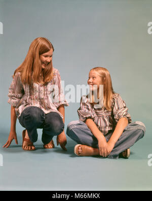 Anni Settanta due ragazze adolescenti sorelle JEANS BLU DENIM CAMICIE CONTADINA SEDUTA E inginocchiato sorridente GUARDANDO OGNI ALTRO - kj6514 HAR001 HARS STUDIO SHOT SALUBRITÀ HOME VITA spazio copia persone bambini amicizia a mezza lunghezza più giovane ragazza adolescente in interni fratelli sorelle DENIM NOSTALGIA convivere 13-15 anni 16-17 anni inginocchiato felicità stili di SVAGO E CAMICIE gemelli sorride gioiosa la moda capelli lunghi adolescente JEANS BLU novellame contadino sandali etnia caucasica OGNI ALTRO VECCHIO PERSONE Foto Stock