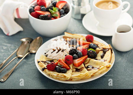 Crespelle sottili con panna montata e frutti di bosco Foto Stock