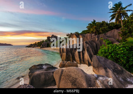 Bel tramonto a incredibili pittoresca spiaggia paradiso. rocce di granito,sabbia bianca, palme,l'acqua turchese al Tropical Beach Anse Source d'argent, la Foto Stock