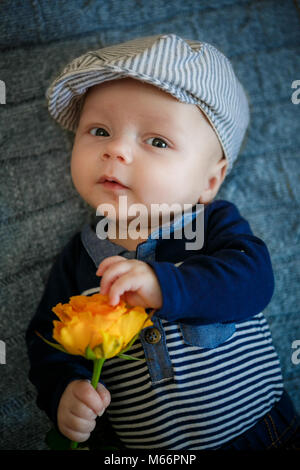 Il ragazzo tiene una rosa gialla in mano in studio Foto Stock