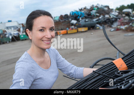 Femmina utilizzando una gru con rifiuti scrapyard auto Foto Stock