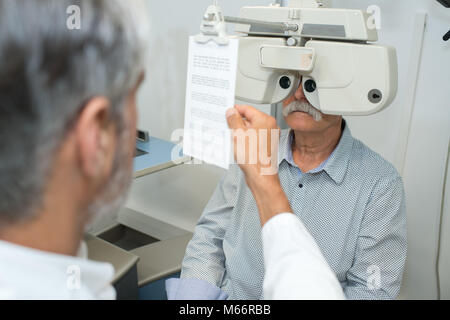 All'ottico optometrista phoropter regolazione per senior paziente di sesso maschile Foto Stock