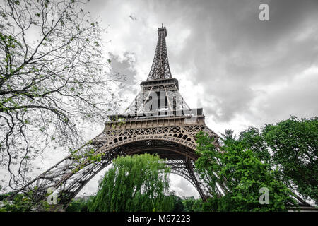 La Torre Eiffel vista dal basso oltre le nuvole scure Foto Stock
