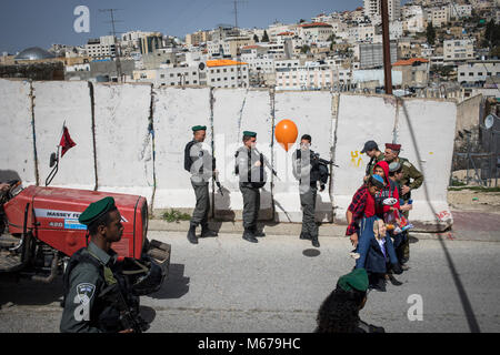 Soldati israeliani guardia come costume i coloni israeliani prendere parte alla parata segna la festa ebraica di Purim in divisa in Cisgiordania città di Hebron, 01 marzo 2018. La carnevalesca Purim holiday è celebrata con sfilate in costume e parti per commemorare la liberazione del popolo ebraico dalla un complotto per sterminarli nell'antico impero persiano 2.500 anni fa, come registrato nel libro biblico di Ester. Foto: Ilia Yefimovich/dpa Foto Stock