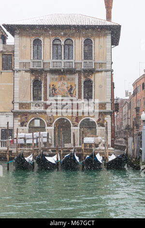 Venezia, Veneto, Italia 1 marzo 2018. Il maltempo oggi a Venezia con temperature sotto zero tra meno 3 e meno 2 e continua la caduta della neve durante tutta la giornata causato dalla Bestia da est o il Siberiano parte anteriore dalla Russia spazzare in tutta l'Europa. Coperta di neve gondole attraccate di fronte a Palazzo Salviati con la sua decorativo in vetro di Murano mosaici sul Grand Canal, Dorsoduro. Foto Stock