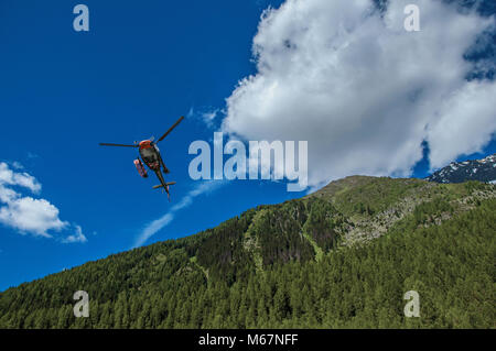 Elicottero di decollare in una foresta a Argentiere, un piccolo villaggio alpino con diversi percorsi di trekking in estate. Vicino a Chamonix nelle Alpi francesi Foto Stock