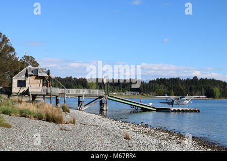 Vista lungo la riva del Lago Te Anau a Te Anau a Southland, Isola del Sud della Nuova Zelanda guardando verso la banchina e pontile con idrovolante sul lago. Foto Stock