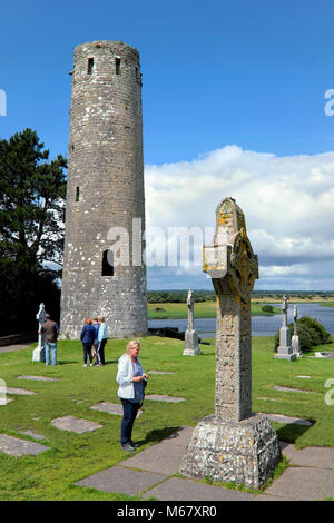 Donna in piedi accanto alla croce delle Scritture, Monastero di Clonmacnoise, nella contea di Offaly, Irlanda Foto Stock