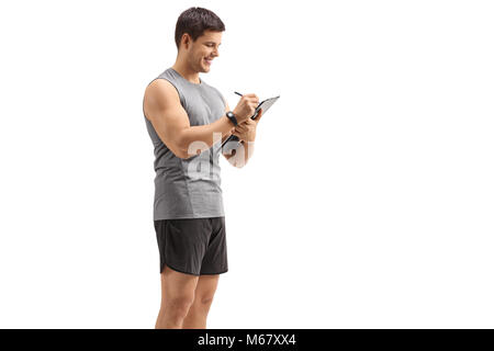 Giovane uomo abbigliamento sportivo in scrittura in un blocco appunti isolati su sfondo bianco Foto Stock