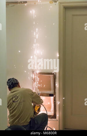 Lavoratore utilizzando acciaio utensile smerigliatrice in appartamento edificio corridoio rinnovo, New York City, Stati Uniti d'America Foto Stock