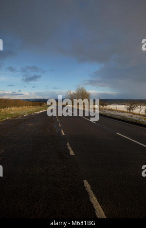 Strada sulla sommità del colle Searby con vedute intorno di neve su un parzialmente nuvoloso giorno nel North Lincolnshire, Regno Unito Foto Stock