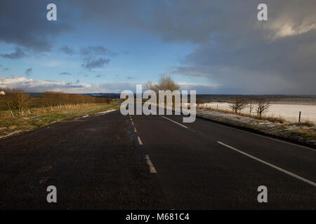 Strada sulla sommità del colle Searby con vedute intorno di neve su un parzialmente nuvoloso giorno nel North Lincolnshire, Regno Unito Foto Stock