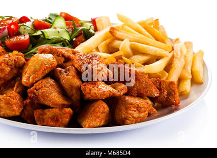 Grigliate di carne con patate fritte e verdure su sfondo bianco Foto Stock