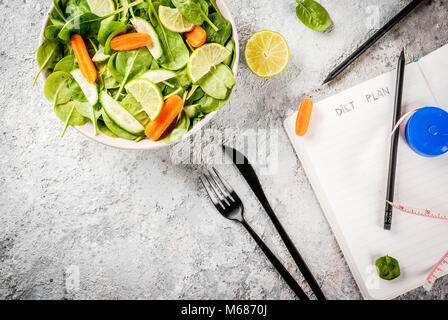 Programma di dieta perdere peso concetto, verdura fresca insalata con forcella, coltello, appunti, pietra grigia copia tabella vista dall'alto dello spazio Foto Stock