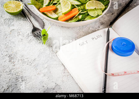 Programma di dieta perdere peso concetto, verdura fresca insalata con forcella, coltello, appunti, pietra grigia copia tabella spazio Foto Stock