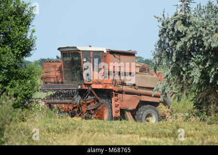 Vecchio arrugginito mietitrebbia. Trebbiatrici mietitrebbia macchine agricole. La macchina per la mietitura di raccolti di grano. Foto Stock