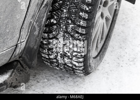 Auto ruota sul pneumatico neve con perni di metallo, che migliorare la trazione sulle superfici ghiacciate nella stagione invernale Foto Stock