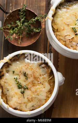 Zuppa di cipolle francese nella tradizionale zuppa di bianco bocce su sfondo di legno Foto Stock