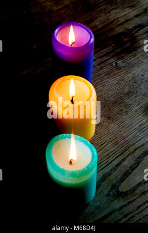 Tre candele colorate su di un tavolo di legno Foto Stock