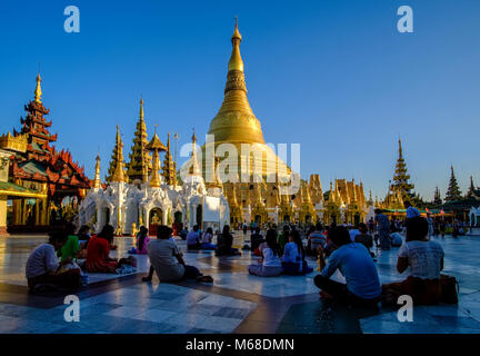 Le persone sono seduti intorno al golden Shwedagon pagoda, il più sacro pagoda di Myanmar, situato su una collina nel centro della città Foto Stock