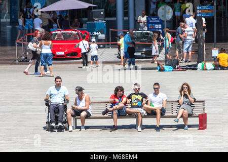 La gente seduta su una panchina presso il centro commerciale Maremagnum vicino al Barcelona Port Vell Foto Stock