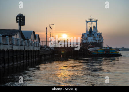 Ocean Liner terra al porto sul fiume che il centro della città sotto il tramonto. Foto Stock