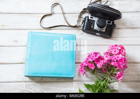 Album blu, bouquet phlox rosa e vecchi film fotocamera su tavola di legno, sopra. Vista dall'alto. Spazio di copia Foto Stock