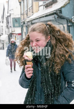 Non è mai a freddo per un gelato anche quando la sua neve, una ragazza gode di un cono gelato in inverno meteo economici Street, Frome, Somerset. Foto Stock