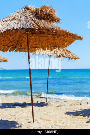 La paglia ombrelloni da spiaggia. Sabbia, mare azzurro e cielo chiaro. Messa a fuoco selettiva su ombrelloni Foto Stock