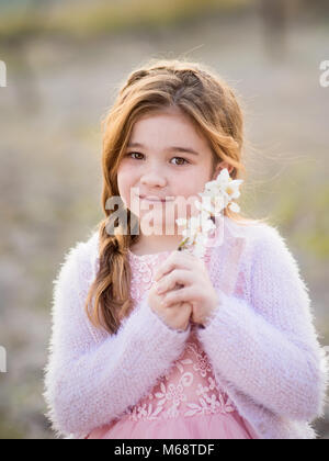 Bambina con fiori di mandorlo nei giardini Foto Stock