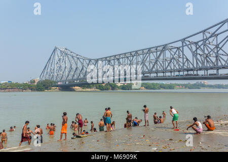 Kolkata, India - 12 Aprile 2017: Unidentified popolo indiano tenendo bagno nel fiume Hooghly con quella di Howrah bridge sullo sfondo a Calcutta, West Bengal, Foto Stock