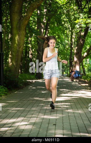 Ragazza adolescente correre, saltare in posizione di parcheggio Foto Stock