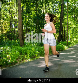 Ragazza adolescente correre, saltare in posizione di parcheggio Foto Stock