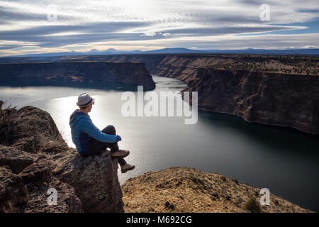 L uomo è seduta sul bordo di una scogliera e godersi il bellissimo paesaggio. Preso al Cove stato Palisades Park in Oregon, Nord America. Foto Stock