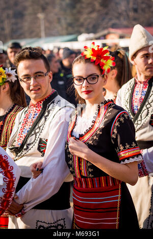 PERNIK, Bulgaria - 26 gennaio 2018: coppia di ballerini folk bulgaro costumi tenere le braccia durante il rituale di marzo presso la soleggiata giornata invernale all'annuale Foto Stock